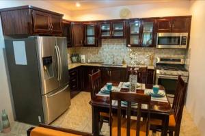 a kitchen with a table and a stainless steel refrigerator at Casa De Llewellyn's Apartments in Kelly Village