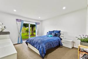 Un dormitorio con una cama azul y una ventana. en Lifestyle Living, en Huapai