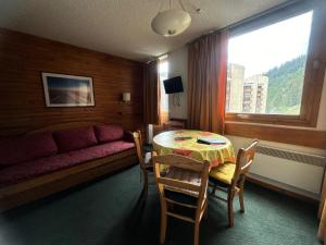 Cette chambre comprend une table, un canapé et une fenêtre. dans l'établissement Résidence Les Glaciers 1 Et 2 - Studio fonctionnel · Accès direct aux pistes · Vue sur la vallée MAE-3778, à Mâcot La Plagne