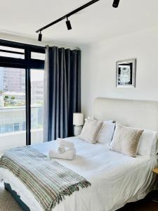 una camera da letto con un letto bianco con una finestra di Stylish 1-Full Bedroom Apartment with a separate Living Room, Workspace and Kitchen close to the beach and V&A in Cape Town a Città del Capo
