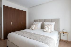 a bedroom with a large white bed with pillows at Luxury Eagle Hills Apartment in Rabat +26 photos