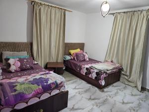 a bedroom with two beds and a window with curtains at Cozy and lovely studio in Cairo