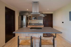 a kitchen with a counter with two chairs and a sink at Jungle Sky Loft in Tulum