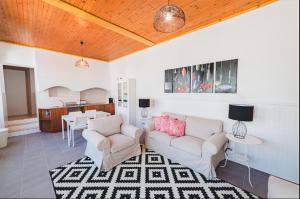 a living room with two couches and a kitchen at Guest House Genuíno in Horta
