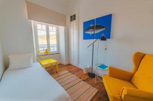a bedroom with a bed and a yellow chair at Guest House Genuíno in Horta