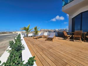 a wooden deck with chairs and tables on a building at MAAR Suites Cotillo in El Cotillo
