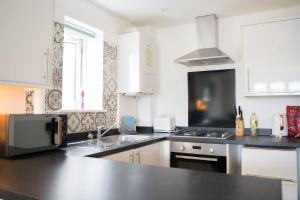 a kitchen with white cabinets and a black counter top at The Kensington Apartment, FREE CarPark, Ideal Location for exploring Oxford City & nearby places, easy access to ring road MINI PLANT, Universities & Oxford Science Parks in Oxford