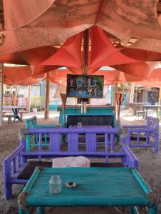 two blue benches sitting under a red umbrella at Zaigon Kite Surf in Máncora