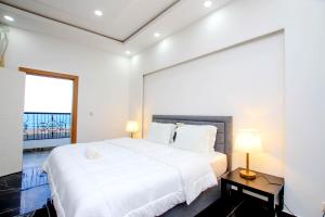 a white bedroom with a large bed and two lamps at America Guest House in Lomé