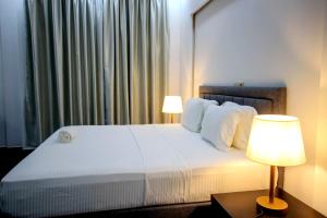 a bedroom with a large white bed with two lamps at America Guest House in Lomé