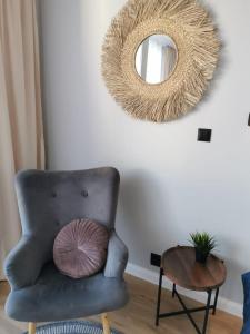 a chair with a pillow and a mirror on a wall at Przytulne Mieszkanie w Centrum in Jastrzębie Zdrój