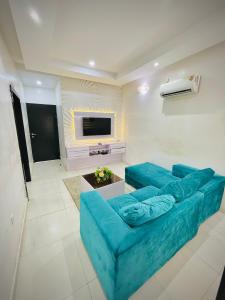 a living room with a blue couch and a tv at Bots Three Bedroom Luxury Apartment in Ilorin
