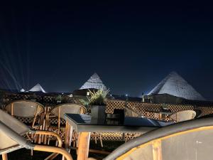 a group of chairs and a table and some pyramids at Nefertari Pyramids View Inn in Cairo