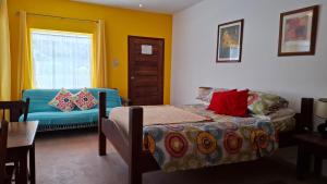 库尔克岛Amanda's Place Yellow Studio - Pool and Tropical garden的一间带床、沙发和窗户的卧室