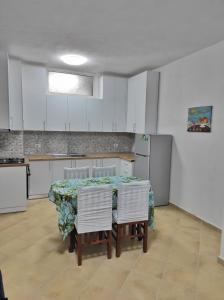 a kitchen with a table and some white cabinets at Noor Apartment in Durrës