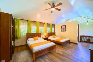 a bedroom with two beds and a ceiling fan at Aninga Lodge in Tortuguero +89 photos