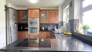 a kitchen with wooden cabinets and stainless steel appliances at Single Room Near Basildon City Centre in Basildon