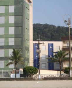 a tall building with palm trees in front of it at Kit no centro de Mongagua em frente o mar in Mongaguá