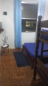 a bedroom with a bed and a window with blue curtains at Kit no centro de Mongagua em frente o mar in Mongaguá