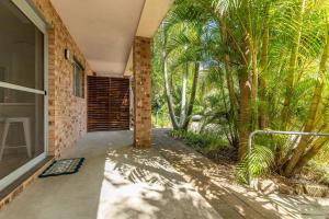 a porch of a house with palm trees at Just Beachy in Boomerang Beach