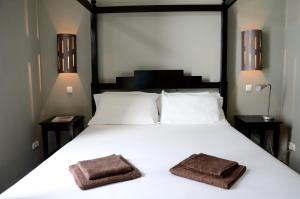 una camera da letto con un grande letto bianco con due asciugamani sopra di Casa Colonial a Mindelo