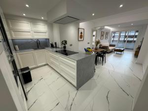 eine Küche mit weißen Schränken und einem Tisch sowie ein Wohnzimmer in der Unterkunft Boabdil Luxury home in Córdoba