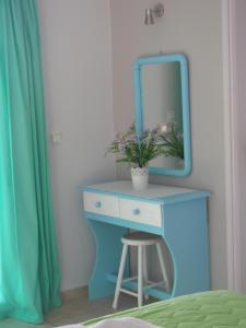 a blue dressing table with a mirror and a stool at Studios Akrogialli in Lipsoi