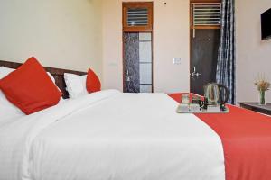 a bedroom with a large white bed with red pillows at Hotel O Kalot in Jaipur +49 photos