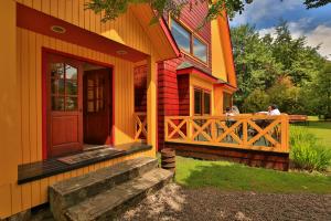an orange house with a porch and a wooden door at Hotel y Cabañas Patagonia Green in Puerto Aisén