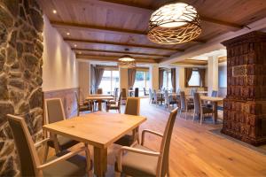 a restaurant with wooden tables and chairs and a stone wall at Chalet Marcora in Campitello di Fassa