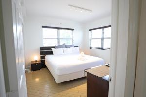 a bedroom with a white bed and two windows at South Beach Walk to Sea Free Parking & Balcony Family & Pet Friendly in Miami Beach