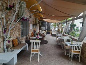 a restaurant with white tables and chairs and a stone wall at Pensao Porta do Vento in Santa Maria