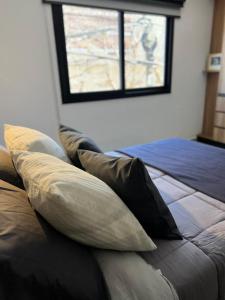 ein Schlafzimmer mit einem Bett mit Kissen und einem Fenster in der Unterkunft JC Apart in Cordoba