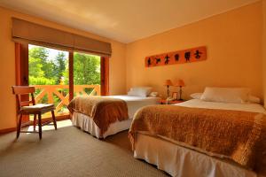 a hotel room with two beds and a balcony at Hotel y Cabañas Patagonia Green in Puerto Aisén