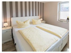 a large white bed with white sheets and a window at Holiday apartment Palstek in Norddeich