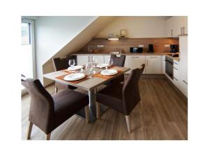 a dining room table with chairs and a kitchen at Holiday apartment Kettenstek in Norddeich