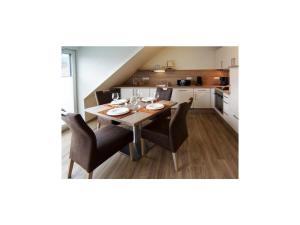 a dining room with a table and chairs and a kitchen at Holiday apartment Kettenstek in Norddeich