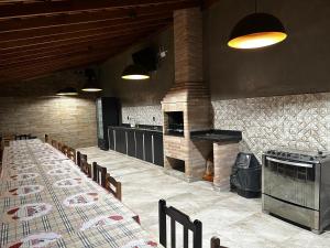 a restaurant with long tables and a brick fireplace at Casa Natalino Broleze in Águas de Lindóia