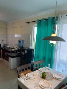 eine Küche mit einem Tisch mit Stühlen und einem grünen Vorhang in der Unterkunft Sunrise Resort Apartments in Mombasa