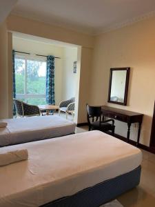 ein Schlafzimmer mit zwei Betten und einem Schreibtisch und einem Spiegel in der Unterkunft Sunrise Resort Apartments in Mombasa + 39 Fotos