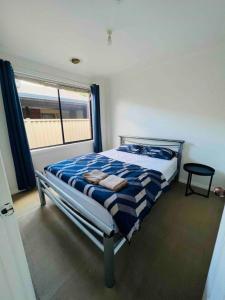 a bedroom with a bed with a blue and white comforter at A spacious Vacation Home nearby Melbourne Airport in Caroline Springs