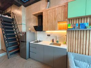 a kitchen with a sink and a refrigerator and a staircase at Comfy Loft at Fairview Apartment Karawaci in Tangerang