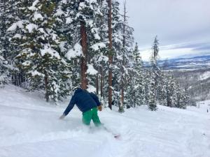 a person on a snowboard in the snow near trees at Iron Horse C3013 condo in Winter Park