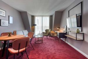 a hotel room with a table and chairs and a living room at Boutique by EMPA in Ulm