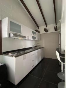 a white kitchen with a sink and a stove at Habitación lago calima Darien in Calima