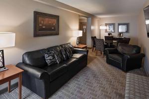a living room with a black leather couch and chairs at Wyndham Bloomington - Mall of America in Bloomington