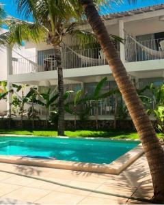 a swimming pool in front of a building with palm trees at Vilamaré Gostoso in São Miguel do Gostoso +24 photos