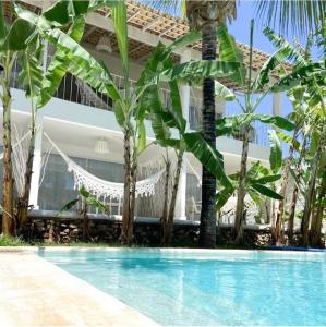 a pool with palm trees in front of a house at Vilamaré Gostoso in São Miguel do Gostoso