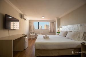 a bedroom with a large white bed and a desk at Rede Andrade Casa Blanca in Fortaleza +31 photos
