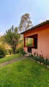 an orange house with a window and a grass yard at Pousada Pedra da Gávea in Visconde De Maua
